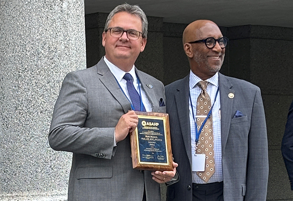 Dr. Mark Merrick, dean of The University of Toledo College of Health and Human Services and acting dean of the College of Nursing, poses with a plaque he received after being named a fellow of the Association of Schools Advancing Health Professions.