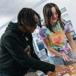 Damian Cosby, left, a sophomore biology student, and Angela Rosillo, a sophomore studying multi-age education, pick out swag at the National Coming Out Day Photoshoot event hosted by the Office of Multicultural Student Success on Friday in the Thompson Student Union.