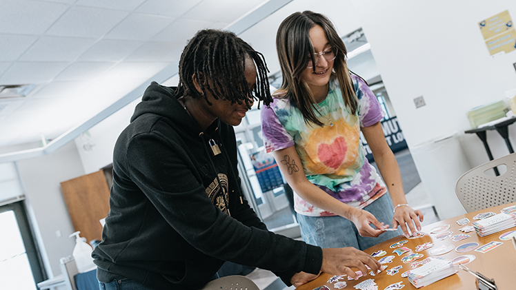 Damian Cosby, left, a sophomore biology student, and Angela Rosillo, a sophomore studying multi-age education, pick out swag at the National Coming Out Day Photoshoot event hosted by the Office of Multicultural Student Success on Friday in the Thompson Student Union.