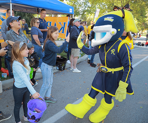 Rocksy interacts with two girls during the 2024 Edward C. and Helen G. Schmakel Homecoming Parade.