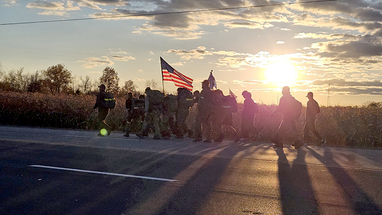 Student Veterans of America groups at The University of Toledo and Bowling Green State University march together along a highway at sunrise to deliver the game ball in their “Ruck the Ball” march leading up to the annual Battle of I-75 football matchup between the Rockets and the Falcons.