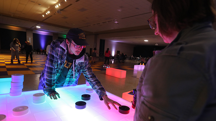 Logan Ostrowski, a sophomore in biomechanical engineering, and his mom, Julie, play glow checkers during the Mom’s Weekend Glow Party in Thompson Student Union Auditorium.