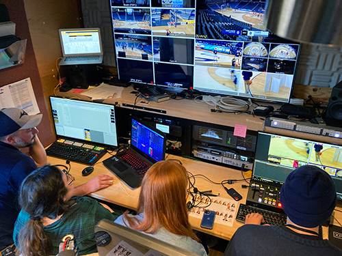 Greg Smith, left, technical director, shows student Cathryn Duran how to operate the Ross XPression graphics system, while fellow student Grace Powell (third from left) teaches her classmate Trip Floyd how to run replay for basketball broadcasts.