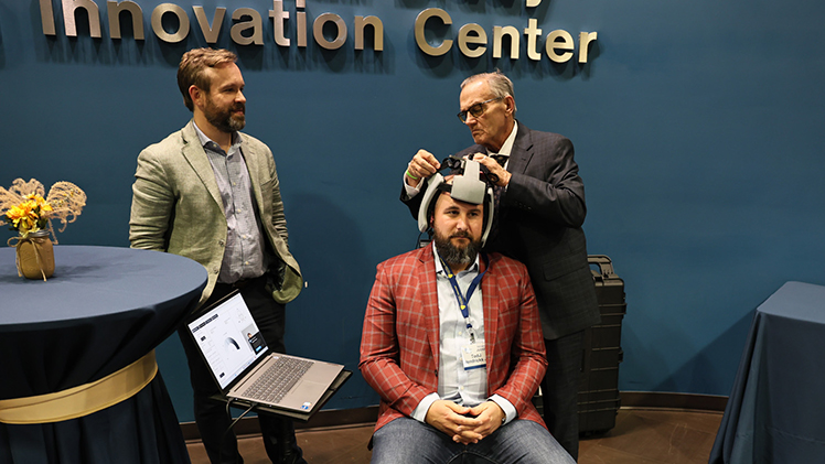 CerviStrength Solutions team members David Uhlenhake, left, a UToledo alumnus, and Dr. Burton Rogers, right, demonstrate their device that tests a patient’s neck strength on Tech419 judge and 2022 pitch competition winner Todd Hendricks Jr.