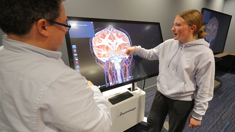 Alyson Albrycht, an undergraduate neuroscience major, reviews structures within the human brain on an Anatomage Table while Dr. James Burkett, an assistant professor of neuroscience in the College of Medicine and Life Sciences, looks on.