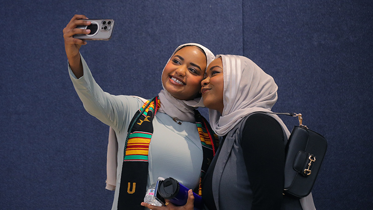 Graduating with a bachelor of science degree in exercise science, Reemaz Siddig, left, takes a selfie with sister Yasmeen Siddig before Thursday evening’s Multicultural Graduation ceremony in Thompson Student Union Auditorium.