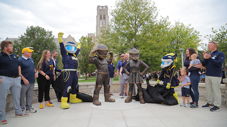 Rocky and Rocksy, depicted in life-sized bronze statues, strike a camera-ready pose along with UToledo officials, former mascots and the real-life Rocky and Rocksy on Centennial Mall ahead of the October Homecoming football game.