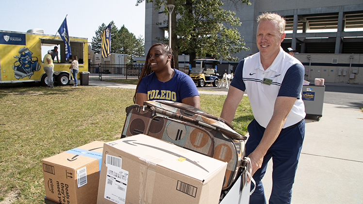 Interim President Matt Schroeder helps Amaiya Thomas, an incoming freshman who will be studying nursing, push her cart of belongings into Parks Tower during August move-in.