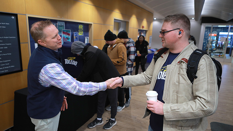 Michael Spears, a junior studying communication, talks with Interim President Matt Schroeder Wednesday afternoon at a hot cocoa station in the lobby of Thompson Student Union.