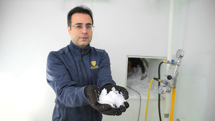 Dr. Hossein Sojoudi, an associate professor and interim chair of the Department of Mechanical, Industrial and Manufacturing Engineering, holds snow created as research using a walk-in freezer connected to a wind tunnel in the College of Engineering.