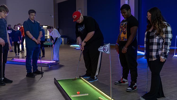 Noah Tillman, a junior nursing student, plays mini golf at CAP's Winter Fest on Tuesday night in Thompson Student Union Auditorium alongside friends, from left, Alexander Gemuenden, a junior studying finance; Noah Tillman, a junior studying nursing; Pierce Dawkins, a junior studying electrical engineering; and Haley Futery, a sophomore studying recreational therapy.