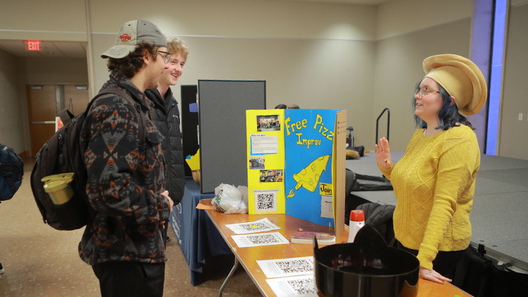 From left, Dante Pellegrino, a professional sales sophomore, and Jack Forynski, a mechanical engineering sophomore, talk with Lauren Adkins, a mechanical engineering senior, at the Free Pizza Improv table at the Spring Campus Involvement Fair.