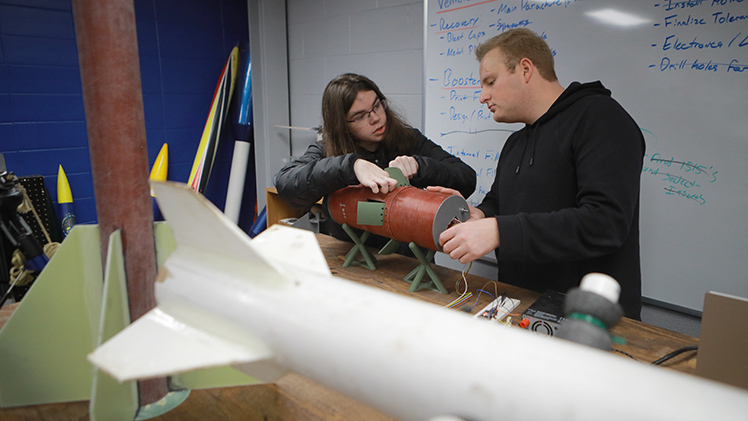 The UToledo Rocketry Club’s Matthew Lomax, a mechanical engineering freshman, and Brody Greenwood, a mechanical engineering senior, tinker with an air braking system that the team is designing for the rocket they will compete in the 2025 NASA Student Launch Challenge.