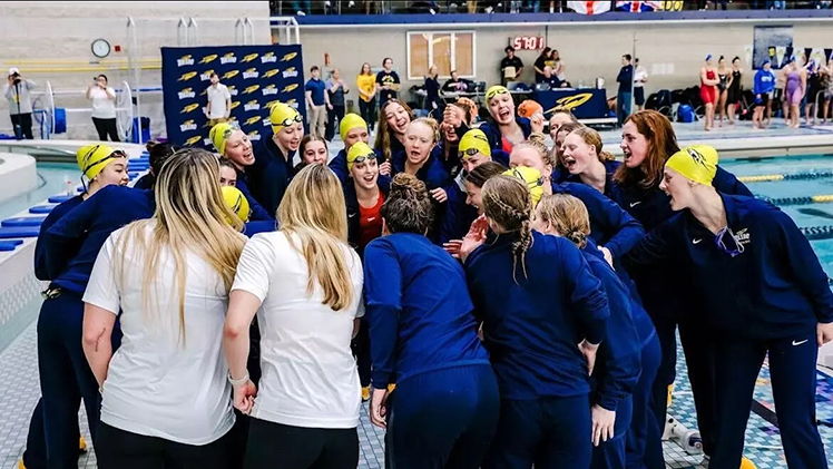 The Toledo Women's Swimming and Diving Team huddle together during a meet.