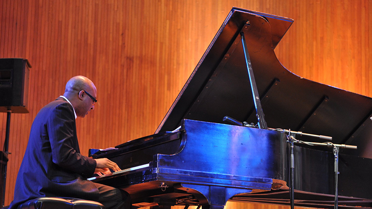 Portrait of Xavier Davis, a celebrated jazz pianist, performing on a piano.