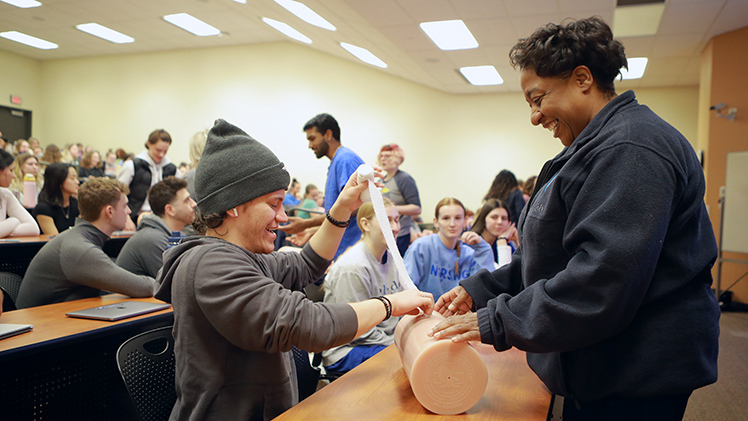 Ebonee Johnson (Lead RN at the Comprehensive Care Center) watches as Jacob Bennett (Senior majoring in Nursing) packs a wound to control bleeding during the Stop the Bleed event.