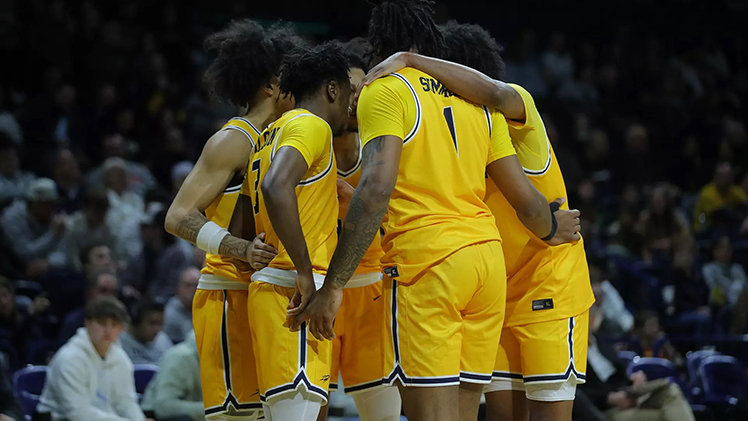 Men's basketball team players huddle together during a game.