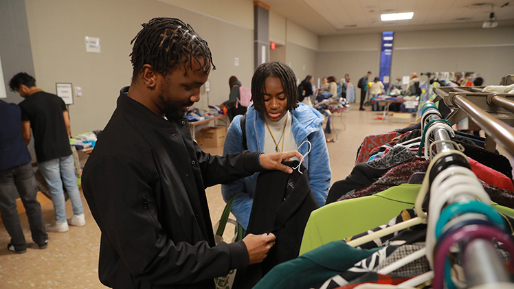 Two UToledo students look at donated shirts on a rack during a Rocket Thrift Shop event.