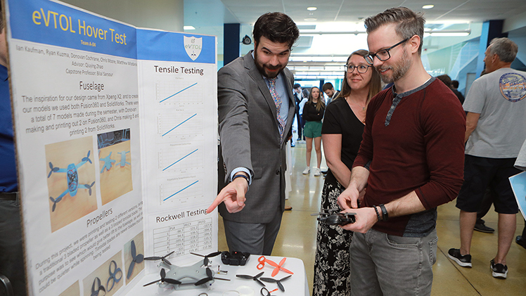 Undergraduate seniors showed off their creativity and ingenuity — and what they’ve learned in years of coursework and co-ops — during the College of Engineering’s Senior Design Expo on Friday, April 25. Among them was Ryan Kuzma, a mechanical engineering technology senior. He explained his team’s senior design project, an eVTOL hover test, to Sara Grzywinski and Kyle Jansen in Nitschke Hall.