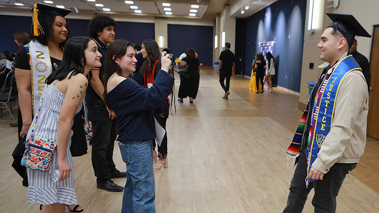 Prior to the start of the Multicultural Graduation ceremony, friends Angela Rosillo and Josie Kuth take a photo of Pavel Lopez-Galindo, who is graduating with a bachelor’s degree in marketing.