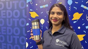 Eshwari Sanjay Ghavare holds a alumni UToledo mug, which will be given to seniors who complete the First Destination Survey.