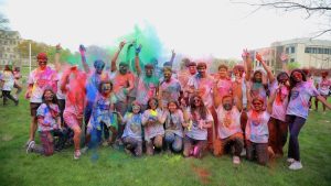 A group of students covered in bright colored powders pose on Centennial Mall.