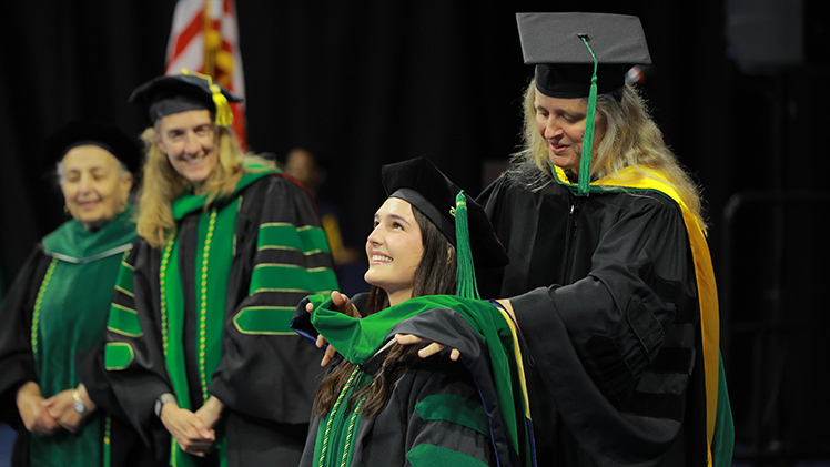 Dr. Martina Blazevic is hooded during the commencement ceremony by Dr. Laurie Gottwald, a professor of medicine in the College of Medicine and Life Sciences, during the college’s commencement ceremony Friday afternoon in Savage Arena. More than 200 students received doctor of medicine, doctor of philosophy or master’s degrees.