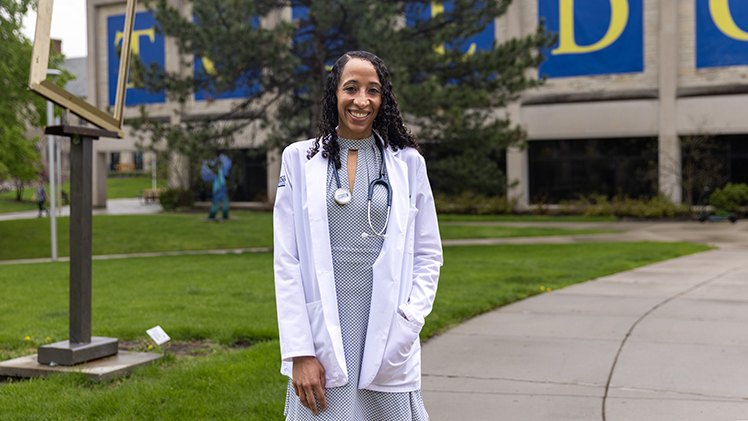 Amy Waters, who will graduate with a medical degree on her 41st birthday, poses for a photo wearing her white medical jacket and a stethoscope and standing in front of Thompson Student Union.