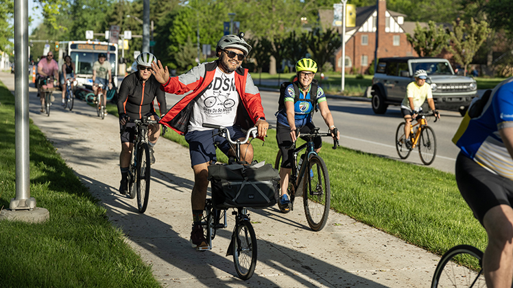 Cyclists wave as they depart UToledo's campus Friday morning during Bike to Work Day.