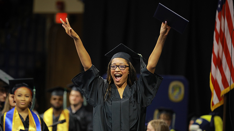 Brooke Lynn Elise Thomas celebrates as she crosses the stage after graduating from The University of Toledo with a bachelor of social work degree during the Saturday morning commencement ceremony in Savage Arena.