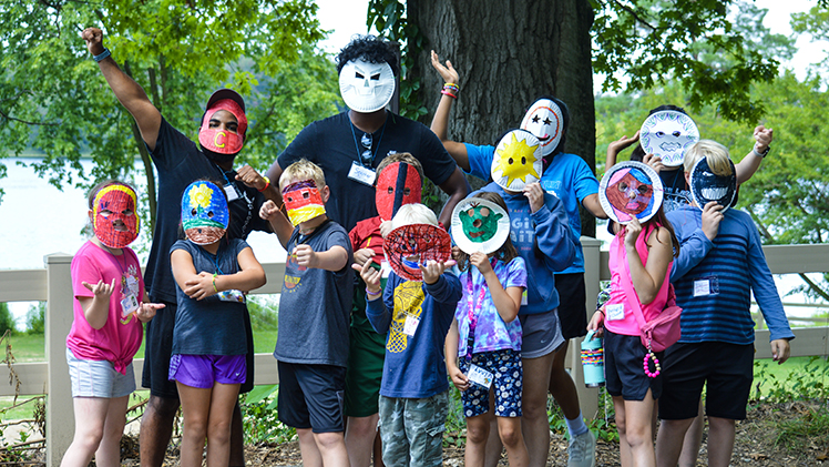 Photo of Camp Kesem counselors and children wearing paper-plate masks.