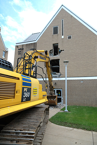 Photo of an excavator as it it begins demolition of the exterior of Sullivan Hall.