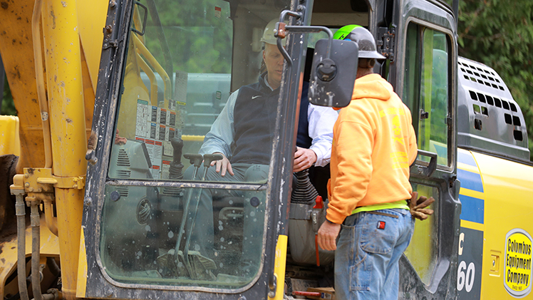 Interim President Matt Schroeder receives final instructions before taking controls of the excavator and beginning demolition of the exterior of Sullivan Hall.