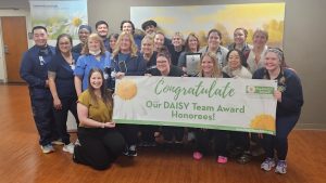 Members of the UTMC Heart and Vascular Unit nursing team hold a banner congratulating them for winning the DAISY Team Award. 