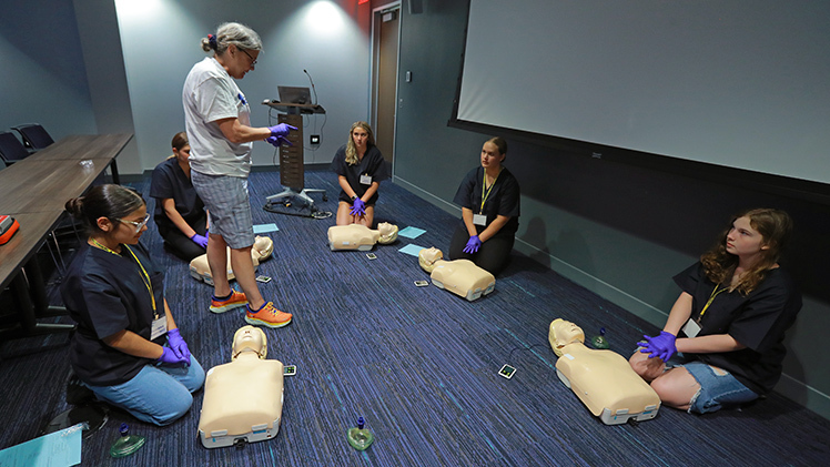 Katie Dollman-Schulz, a registered nurse who teaches basic life support at UToledo, works with CampMed participants on the proper technique for giving chest compressions as part of a CPR class taught during CampMed last week.