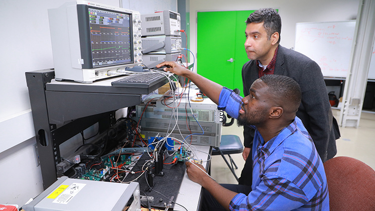 Photo of Samuel Atwimah, a Ph.D. student in electrical engineering, and Dr. Raghav Khanna, the Leidich Family Endowed Professor of Power Systems in the College of Engineering, working on research.