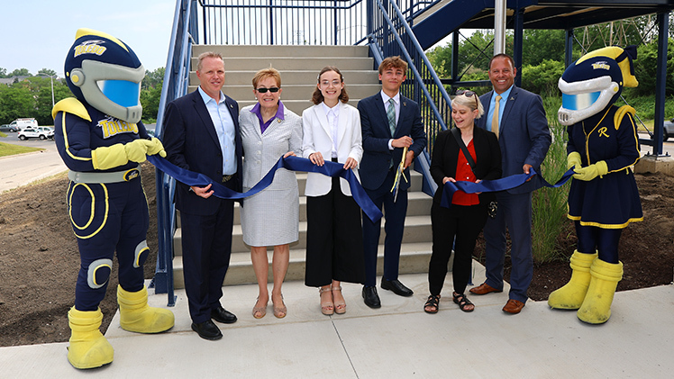 Photo of the UToledo ribbon cutting ceremony for the new bridge, featuring, from left, Rocky, Interim President Matt Schroeder, U.S. Rep. Marcy Kaptur, student body president Iryna Snahoshchenko, student body vice president Jaden Bollinger, Ohio Rep. Michele Grim, Jason Toth, senior associate vice president for administration, and Rocksy.