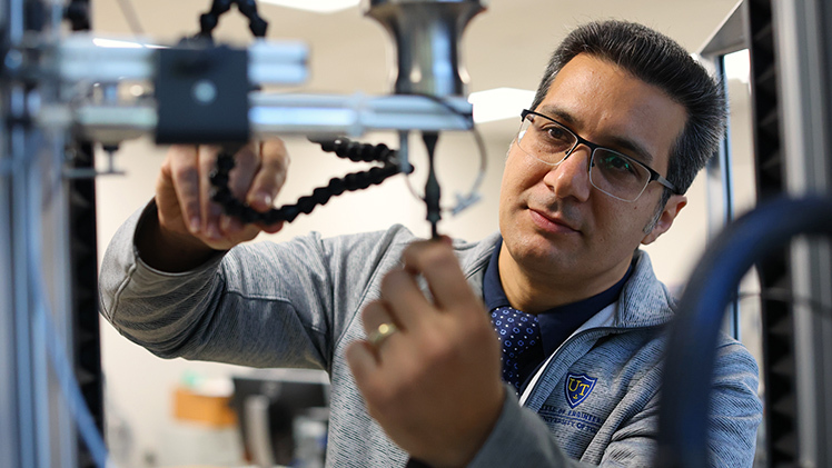 Photo of Dr. Meysam Haghshenas in his lab, He heads the College of Engineering’s Failure, Fracture and Fatigue Laboratory, where he uses high-tech equipment to study how materials weaken under repeated stresses or strains.