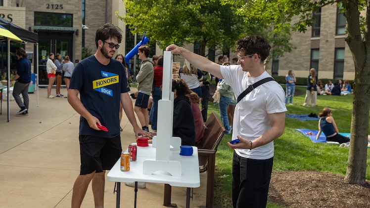 Payton Schmitz, a senior media communication major, and Jacob Wells, a senior bioengineering major, play connect four at HAV's welcome back picnic.