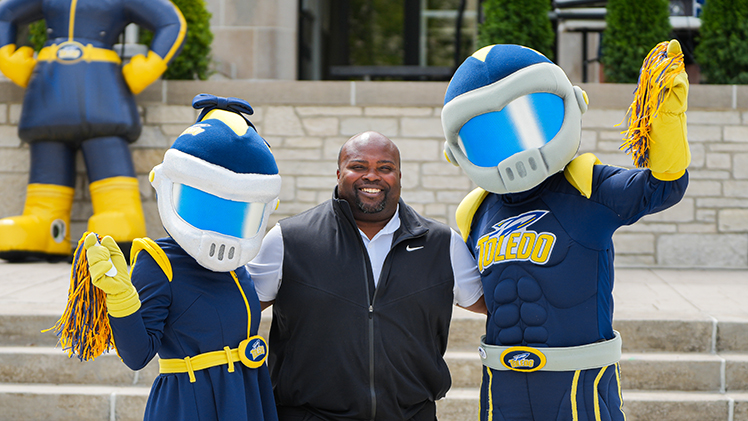 Vice President and Director of Athletics Bryan B. Blair stands between UToeldo mascots, Rocksy and Rocky, as they pose for a photo.
