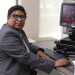 Dr. Charles Thodeti, professor in the College of Medicine and Life Sciences, sits at a digital microscope in his lab on UToledo's Health Science Campus.