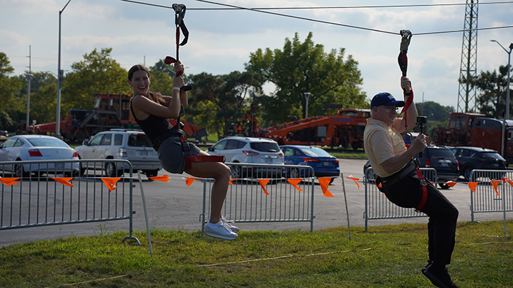 Anna McClure, a freshman majoring in radiation therapy, zip-lines with UToledo President James Holloway, at the CAP Carnival Friday evening at Carter Field. The carnival, which was for all students, featured rides, games and food.