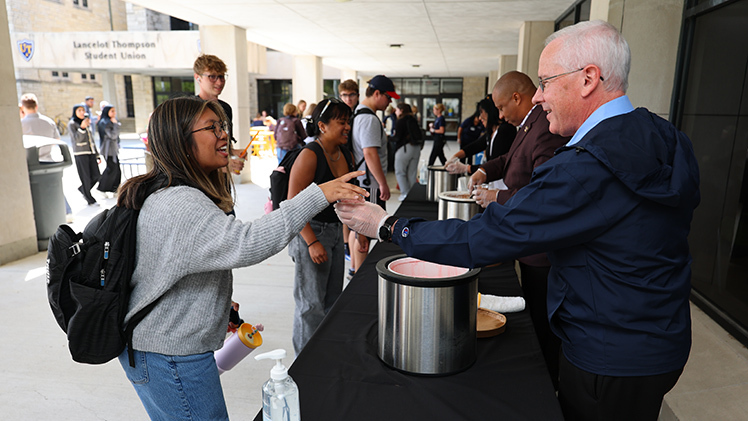 Jillian Micua, a senior studying public health in the College of Health and Human Services, receives a cup of strawberry ice cream from UToledo President James Holloway on Monday afternoon during the annual Sundaes on a Monday at Centennial Mall as part of the Welcome Weeks events that kick off the fall 2025 semester.