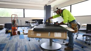 Jason Beebe, a journeyman carpenter with the Lathrop Company, stands in front of a TV he's preparing to install inside Carlson Library.