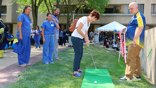 Karen Wisniewski, an X-ray technologist at the University of Toledo Medical Center, plays mini golf during Thursday’s annual Employee Appreciation Summerfest 2025 as UTMC Chief Operating Officer Russell Smith looks on.