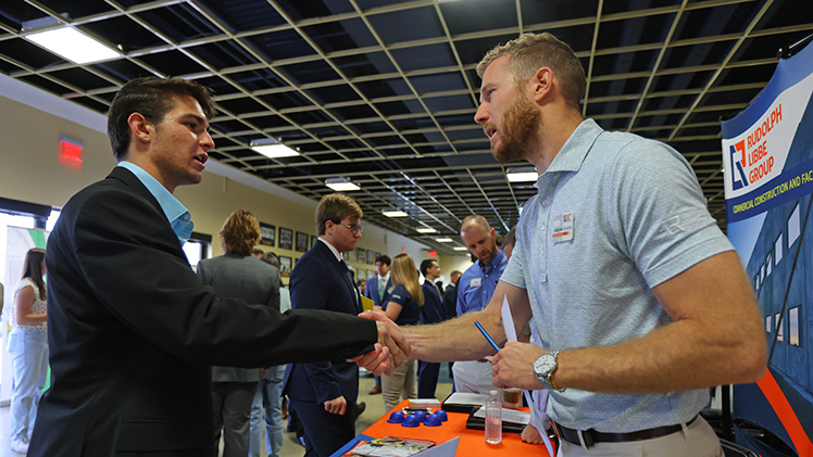 Landon Miller, left, a sophomore studying civil engineering, shakes hands with Christian Simpson, a representative with the Rudolphe Libbe Group, during Thursday’s Fall 2025 Engineering Career Expo in Savage Arena.