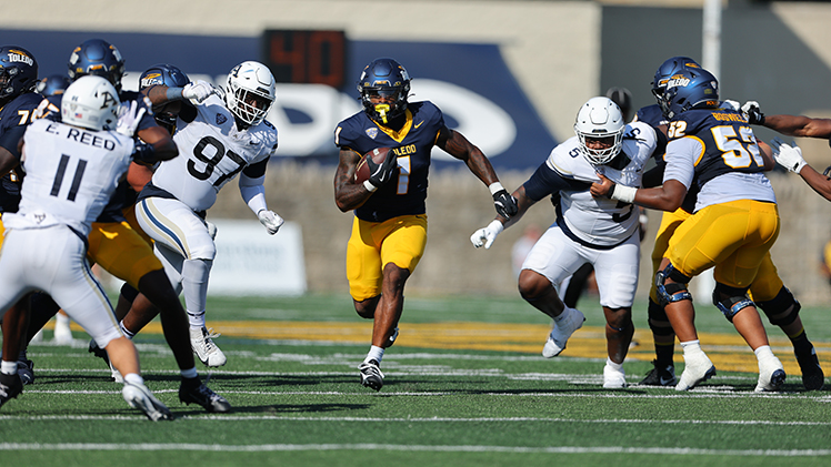 Toledo running back runs through an opening in the line of scrimmage.