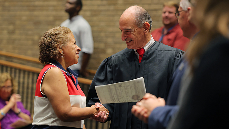 Judge Jack Zouhary of the U.S. District Court for the Northern District of Ohio presided over a ceremony featuring guest speakers and music provided by the UToledo Chamber Singers. Zouhary shook hands with each new citizen, including Carmelina Bernier.