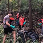 Several volunteers from UToledo, many wearing orange vests, pick up trash during the 2024 Clean Your Streams event.