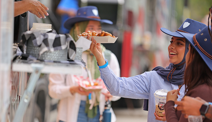 Layla Awethe, a sophomore studying accounting, collects her food from the Detroit Mini Donut food truck on Tuesday afternoon during the Eat the Streets on Centennial Mall.